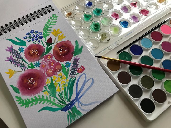 Watercolour painting of a bunch of flowers. Open paint box and brush are beside the painting.