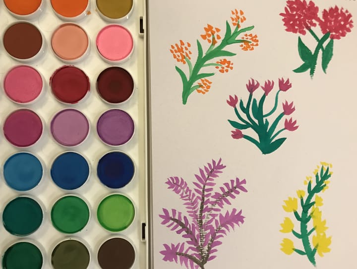 Watercolour paints next to a page of watercolour flowers.