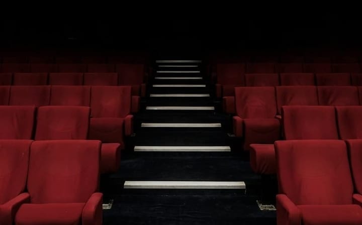 Cinema aisle with rows of red seats on either side.