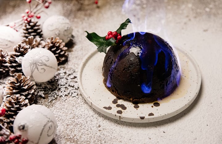 Christmas pudding with flames and a sprig of holly.